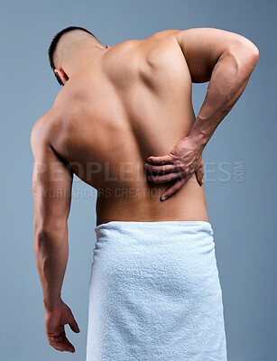 Buy stock photo Rearview shot of an unrecognizable man experiencing backache after his shower against a grey background