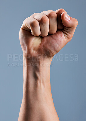 Buy stock photo Shot of an unrecognizable man holding his fist up against a grey background
