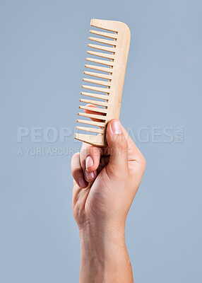 Buy stock photo Shot of an unrecognizable man holding a comb against a blue background