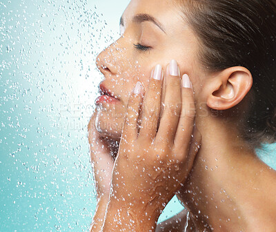 Buy stock photo Shot of a young woman taking a shower against a blue background