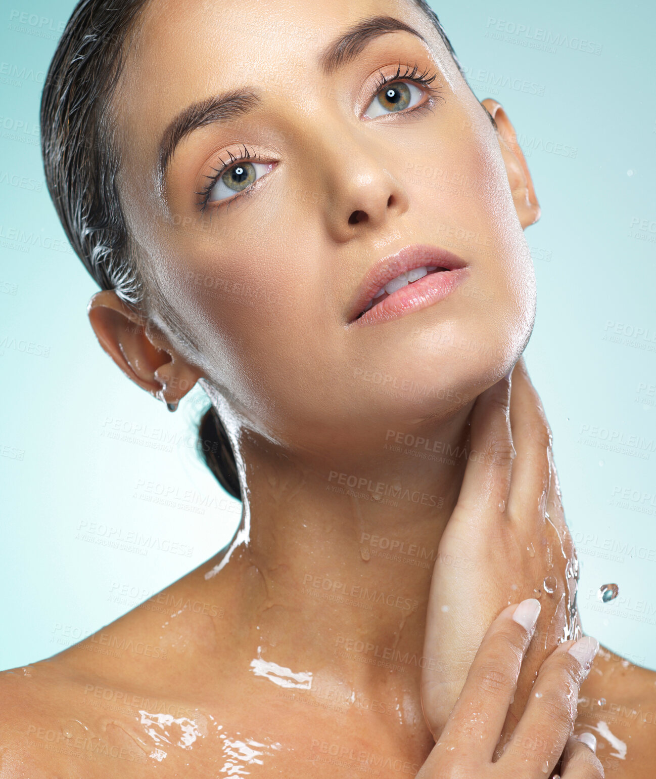 Buy stock photo Shot of a young woman taking a shower against a blue background