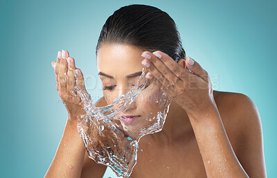 Buy stock photo Shot of a young female washing her face against a blue background