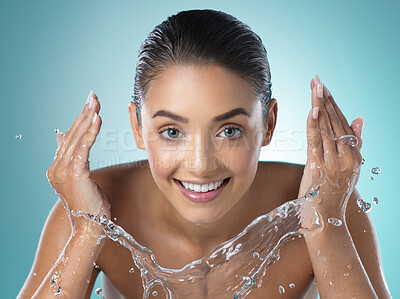 Buy stock photo Shot of a young female washing her face against a blue background