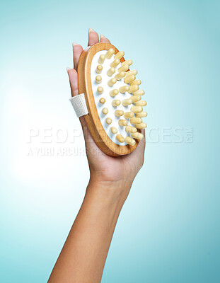 Buy stock photo Shot of an unrecognisable woman holding a body brush against a blue background in the studio