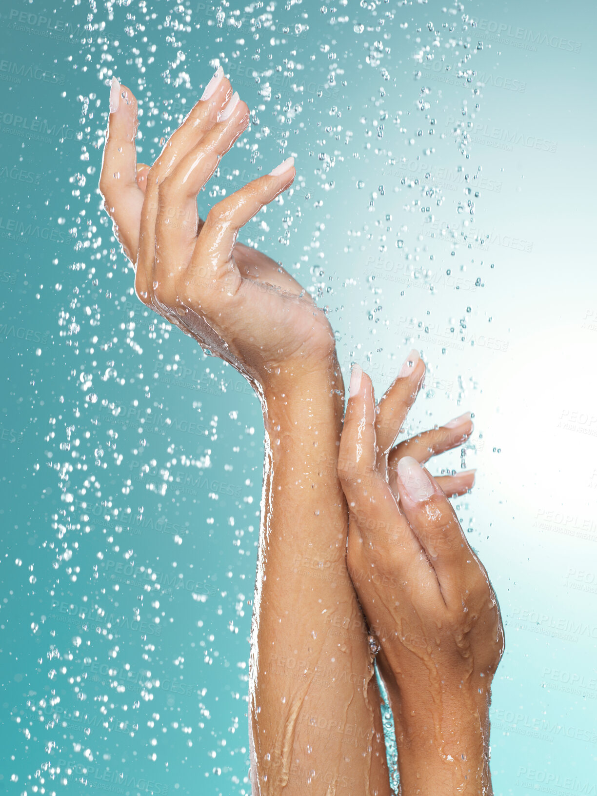 Buy stock photo Shot of hands held out under a stream of water against a blue background