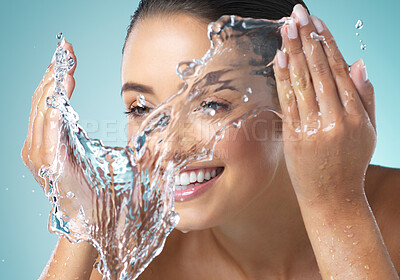 Buy stock photo Shot of a young female washing her face against a blue background