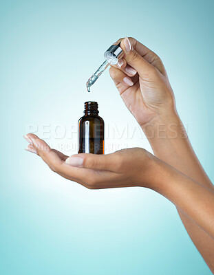 Buy stock photo Shot of a young woman taking serum from a dropper against a grey background