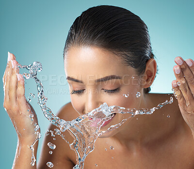 Buy stock photo Shot of a young female washing her face against a blue background