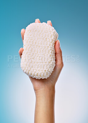 Buy stock photo Cropped shot of an unrecognisable woman holding a sponge against a blue background in the studio