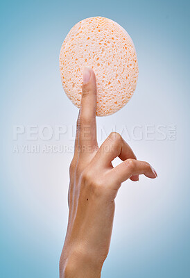 Buy stock photo Cropped shot of an unrecognisable woman holding an exfoliating facial sponge against a blue background in the studio