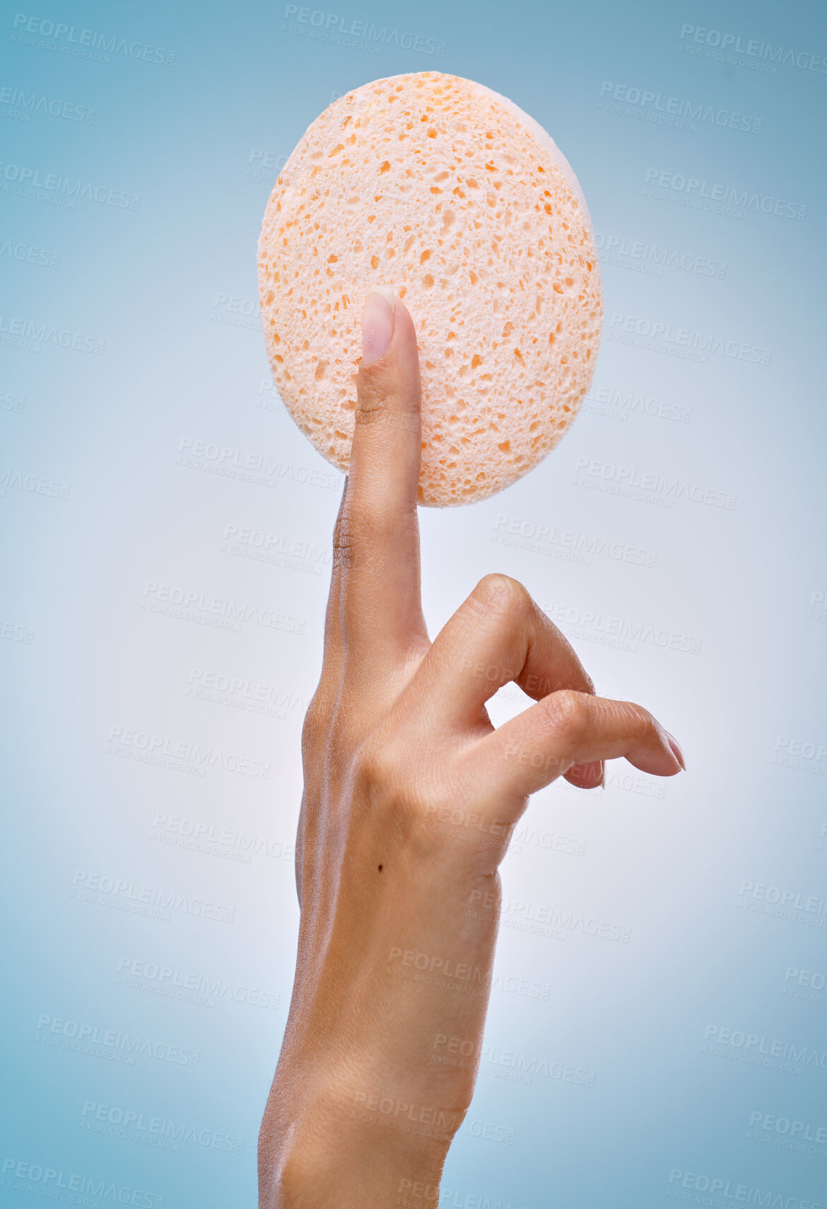 Buy stock photo Cropped shot of an unrecognisable woman holding an exfoliating facial sponge against a blue background in the studio