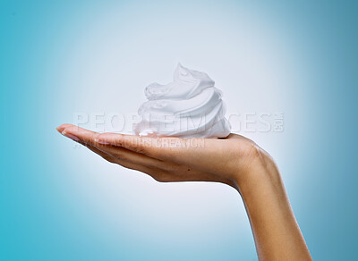 Buy stock photo Cropped shot of an unrecognisable woman holding a handful of shaving cream against a blue background in the studio