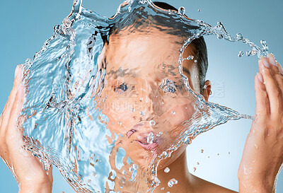 Buy stock photo Shot of an unrecognisable woman posing against a blue background in the studio and splashing her face with water