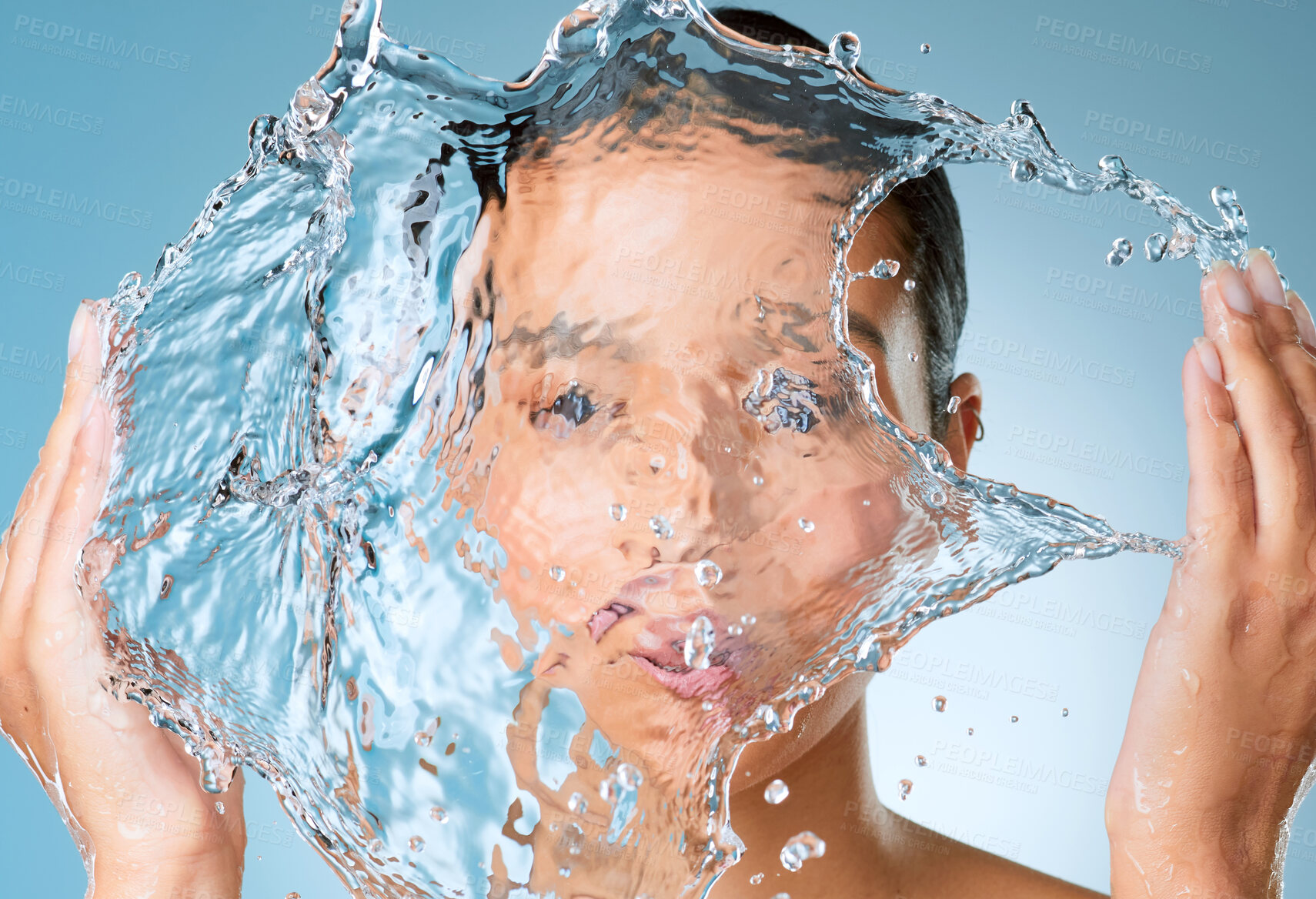 Buy stock photo Shot of an unrecognisable woman posing against a blue background in the studio and splashing her face with water