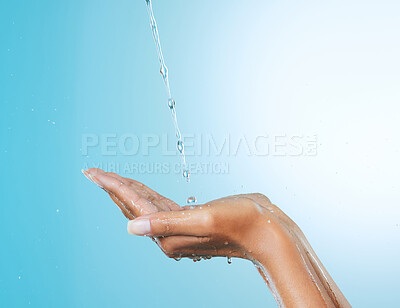 Buy stock photo Cropped shot of an unrecognisable woman cupping her hands to catch water against a blue background in the studio