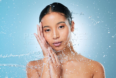 Buy stock photo Shot of an attractive young woman posing against a blue background in the studio while being splashed with water