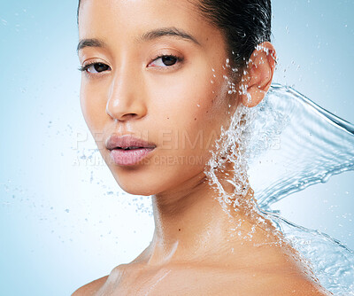 Buy stock photo Shot of an attractive young woman posing against a blue background in the studio while being splashed with water