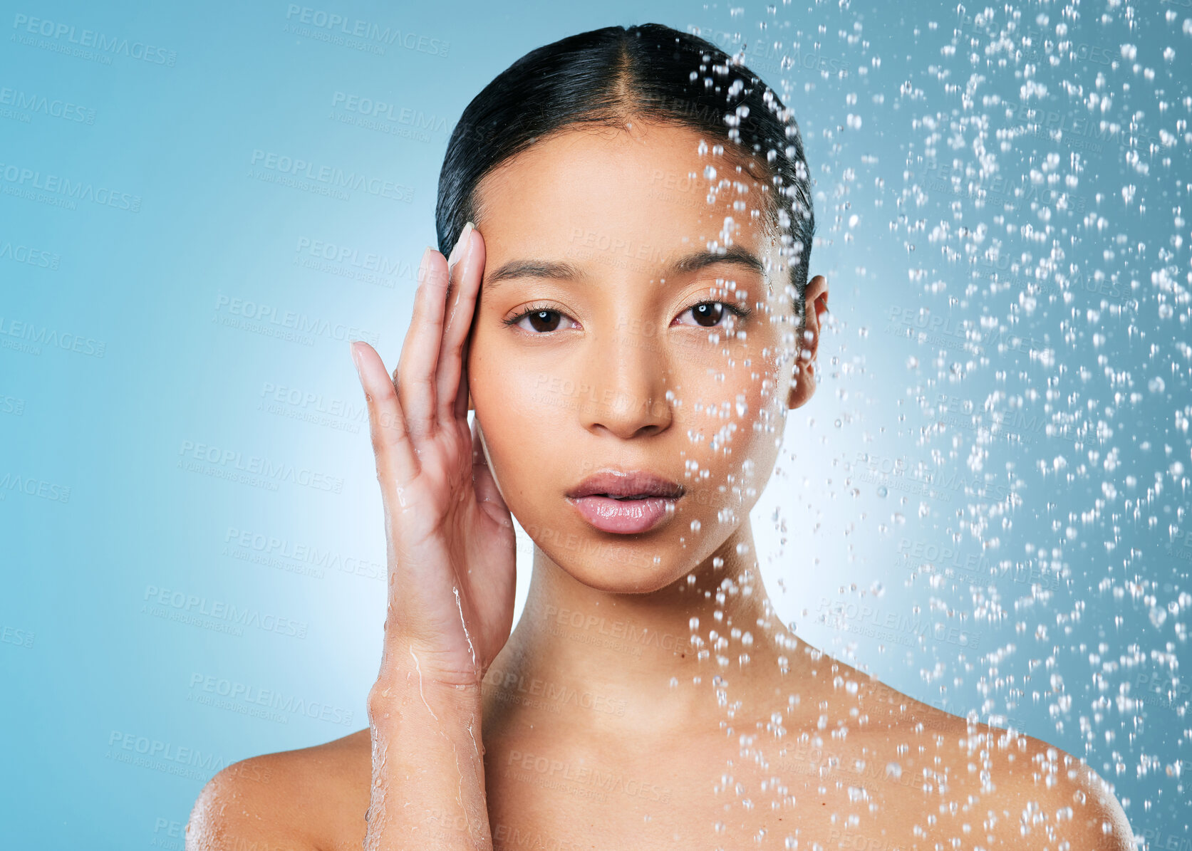 Buy stock photo Shot of an attractive young woman posing against a blue background while taking a shower