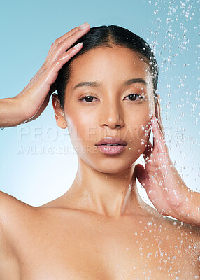 Buy stock photo Shot of an attractive young woman posing against a blue background while taking a shower