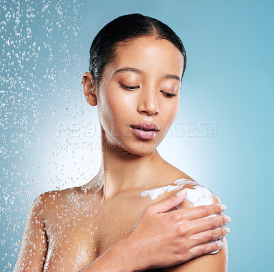 Buy stock photo Shot of an attractive young woman using a body wash while taking a shower against a blue background