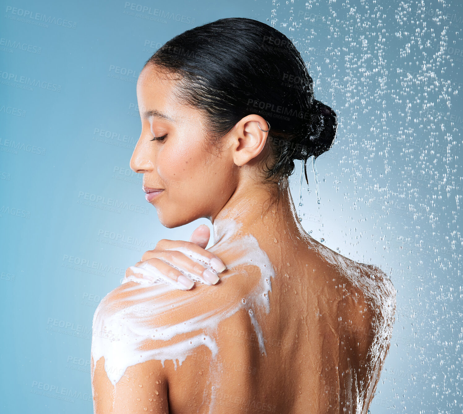 Buy stock photo Shot of an attractive young woman showering against a blue background