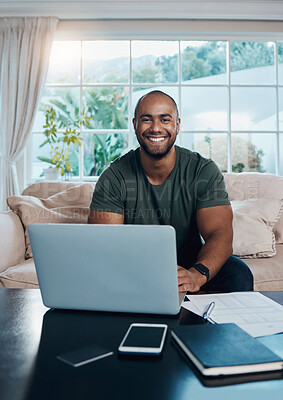 Buy stock photo Shot of a young man working on his laptop in his living room