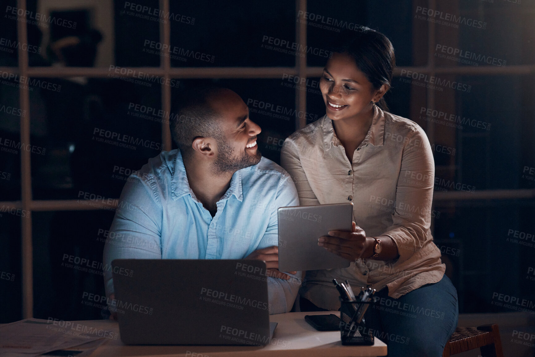 Buy stock photo Shot of a young couple using a digital tablet together at night