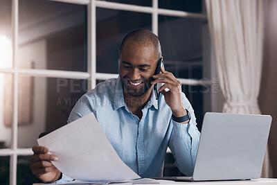 Buy stock photo Shot of a young businessman reading paperwork while making a phone call using his smartphone