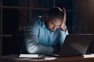 Buy stock photo Shot of a young businessman looking stressed while working on his laptop late at night