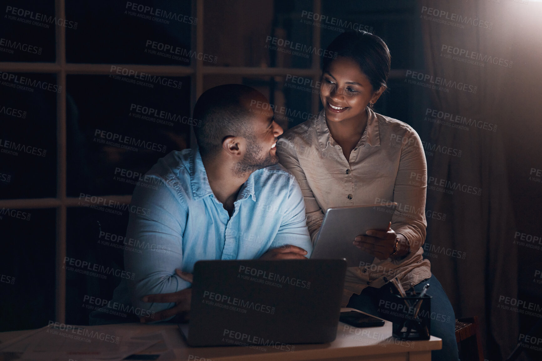 Buy stock photo Shot of a young couple using a digital tablet together at night