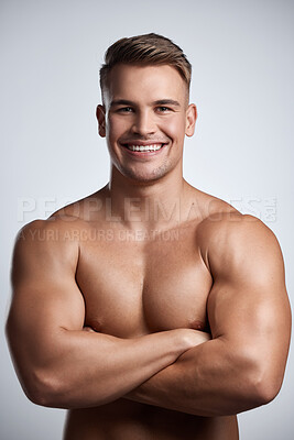 Buy stock photo Studio portrait of a muscular young man posing with his arms crossed against a grey background