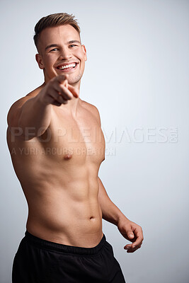 Buy stock photo Studio portrait of a muscular young man pointing to the camera against a grey background