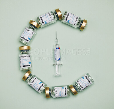 Buy stock photo Shot of vaccines and a syringe against a green background