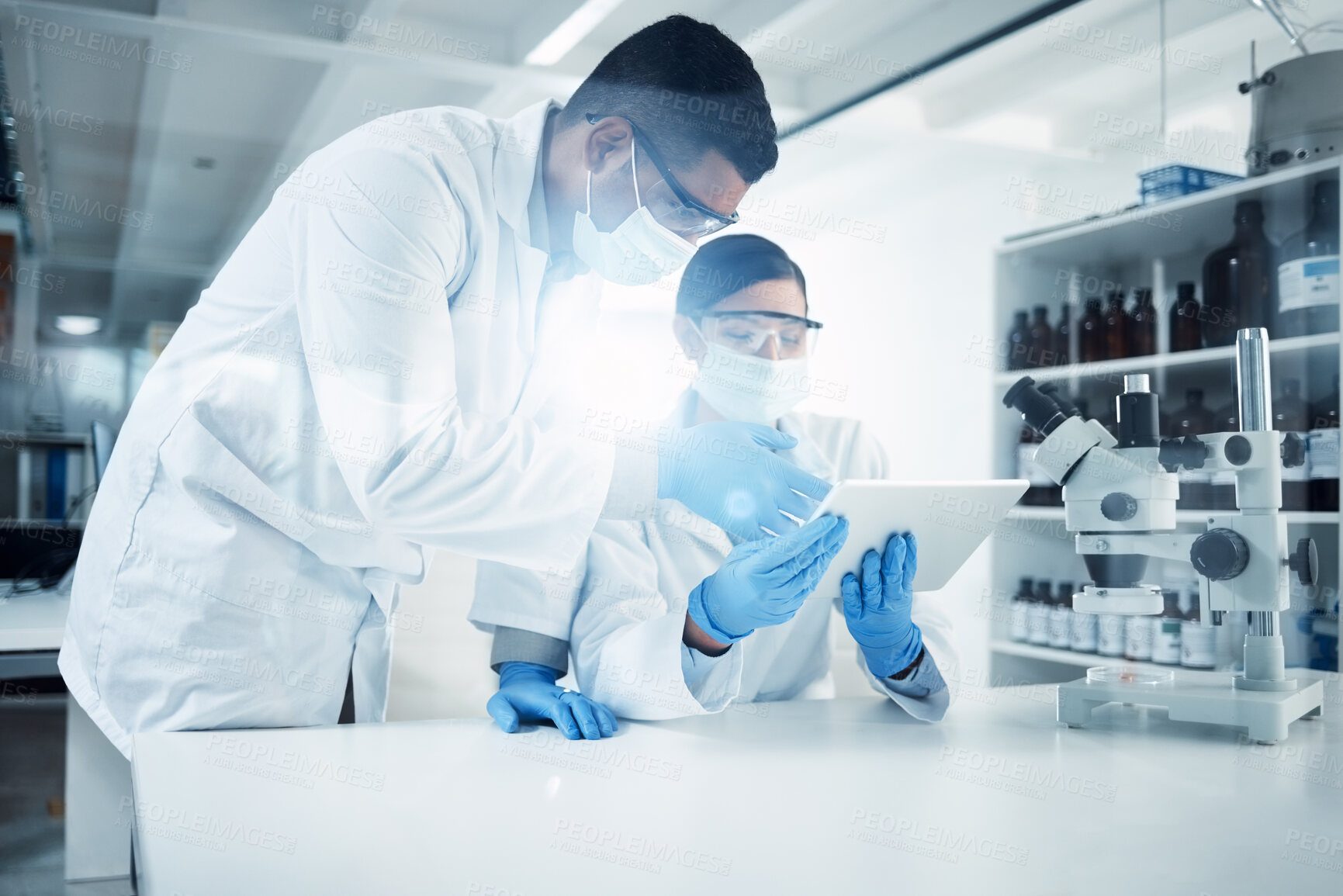 Buy stock photo Shot of two young scientists using a digital tablet while conducting medical research in a laboratory