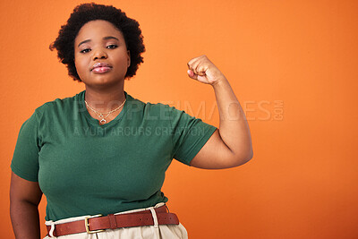 Buy stock photo Shot of a beautiful young woman flexing while standing against an orange background