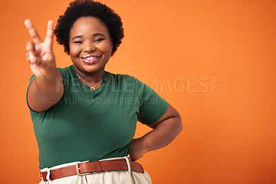 Buy stock photo Shot of a beautiful young woman showing the peace sign while standing against an orange background