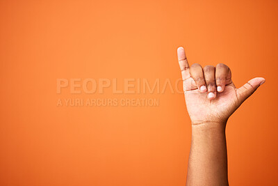 Buy stock photo Shot of an unrecognizable person showing a shaka sign against an orange background