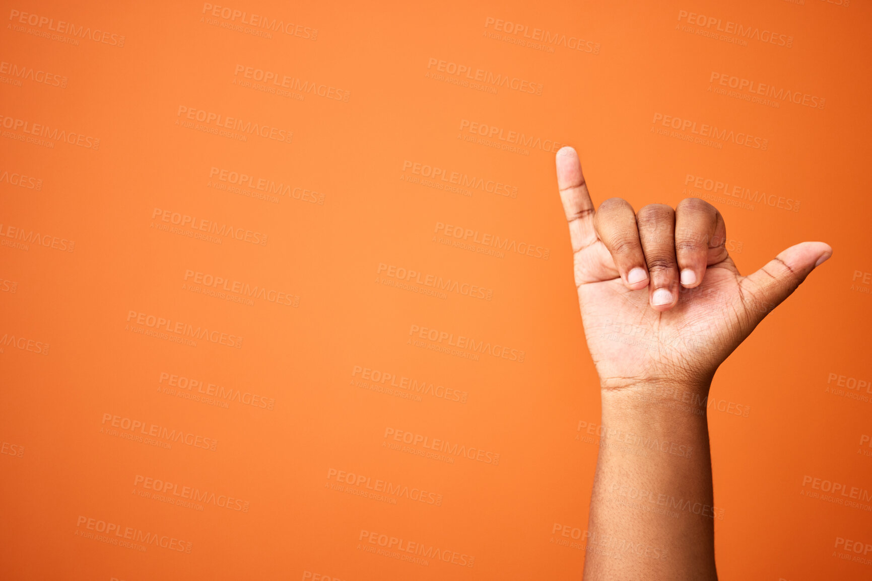 Buy stock photo Shot of an unrecognizable person showing a shaka sign against an orange background