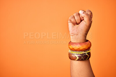 Buy stock photo Shot of an unrecognizable person holding up a fist against an orange background