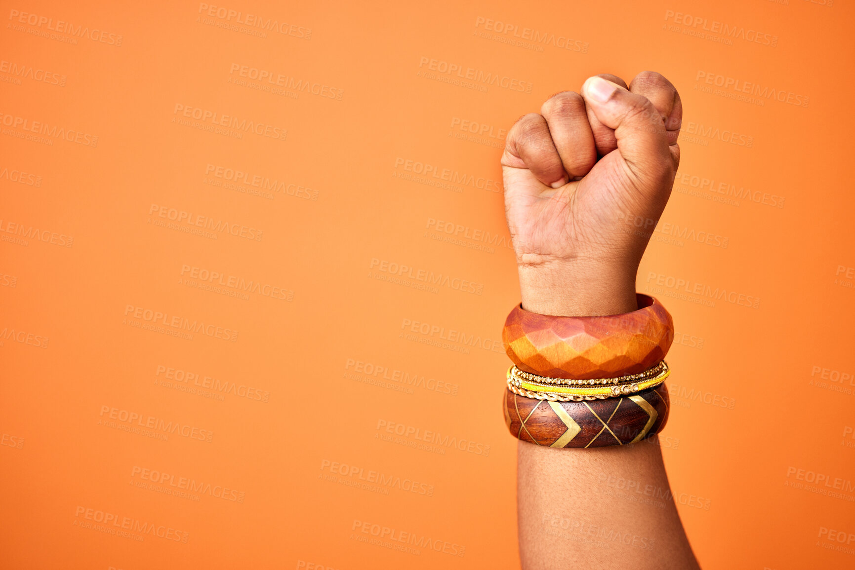 Buy stock photo Shot of an unrecognizable person holding up a fist against an orange background