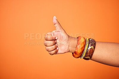 Buy stock photo Hand, thumbs up and person with arm on orange background for thank you or confirm with gesture or sign. Good news, expression and positive with yes or thanks with win in studio for agreement.