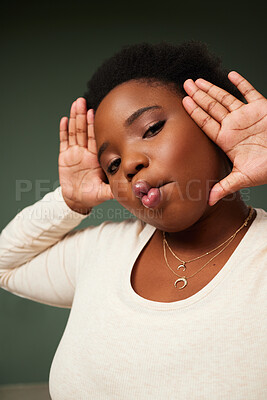 Buy stock photo Shot of an attractive young woman pulling a funny face while posing against a green background in the studio