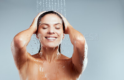 Buy stock photo Shot of a young woman washing her hair in the shower against a grey background