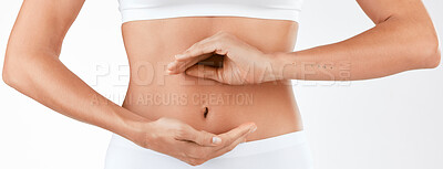 Buy stock photo Shot of a woman holding her hands in a circular shape in front of her stomach against a studio background