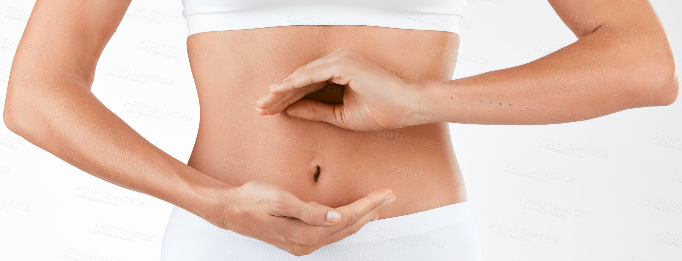 Buy stock photo Shot of a woman holding her hands in a circular shape in front of her stomach against a studio background