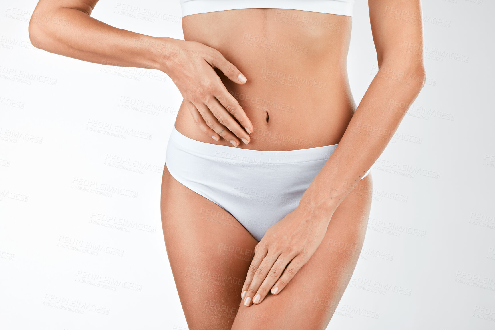 Buy stock photo Shot of a woman touching her stomach against a studio background