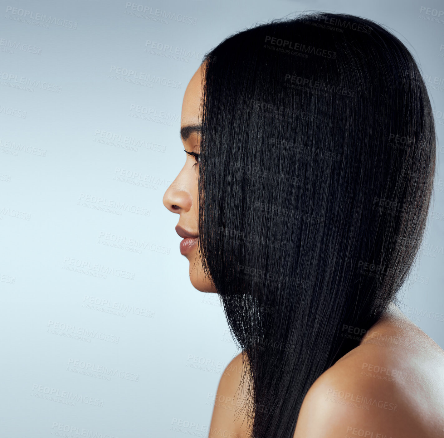 Buy stock photo Side shot of a beautiful young woman posing against a blue background