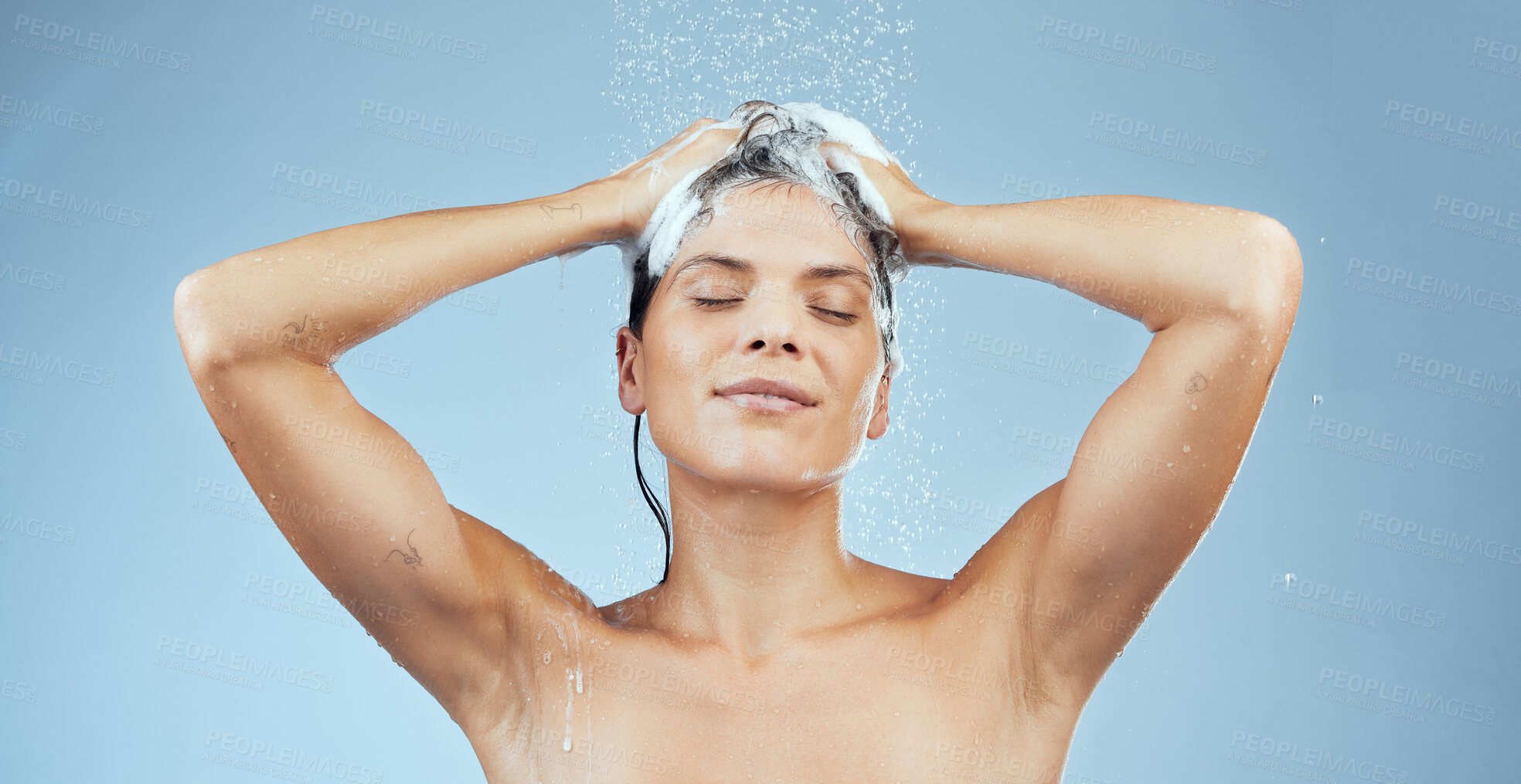 Buy stock photo Shampoo, woman and washing hair with smile for wellness, shower and soap on blue backdrop for routine. Happy, female person and water in studio for beauty, hygiene and clean in morning with splash 