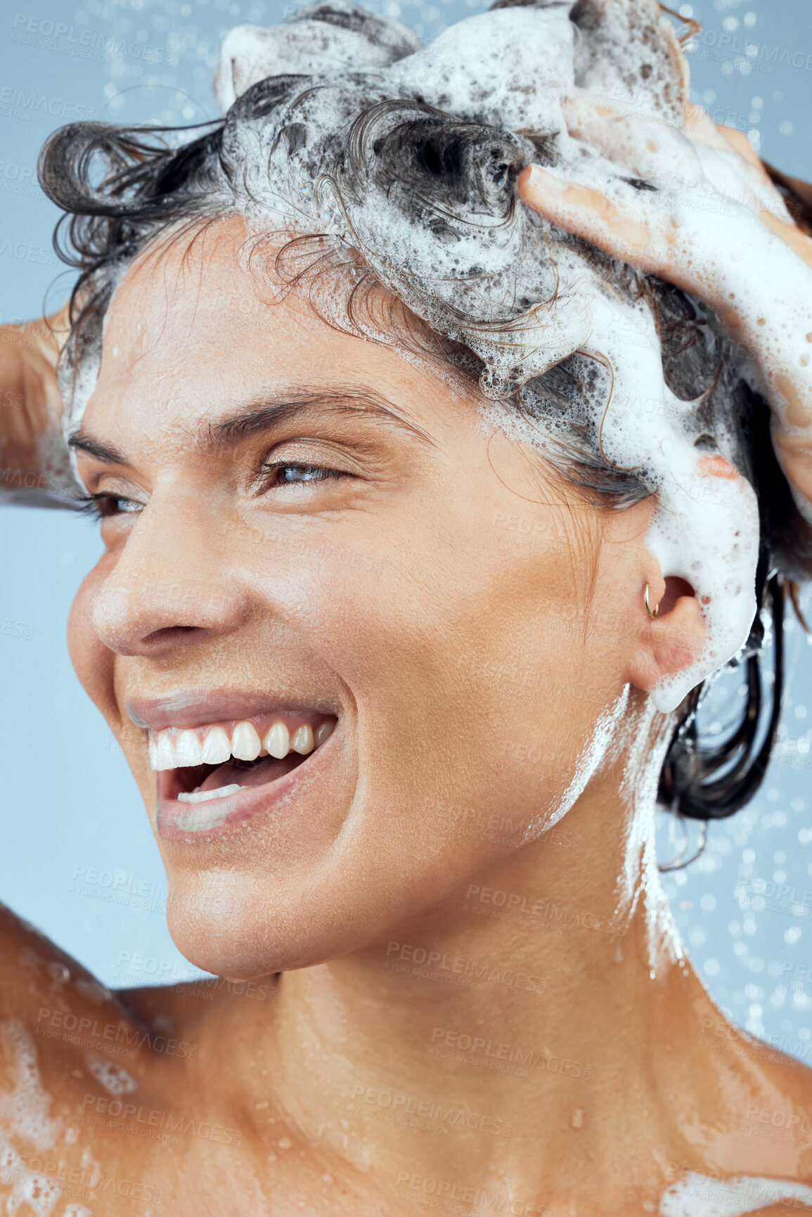 Buy stock photo Shampoo, woman and washing hair with happy for wellness, shower and soap on blue backdrop for routine. Smile, female person and water in studio for beauty, hygiene and cleaning in morning with foam 