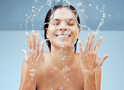 Buy stock photo Studio shot of an attractive young woman washing her face against a blue background